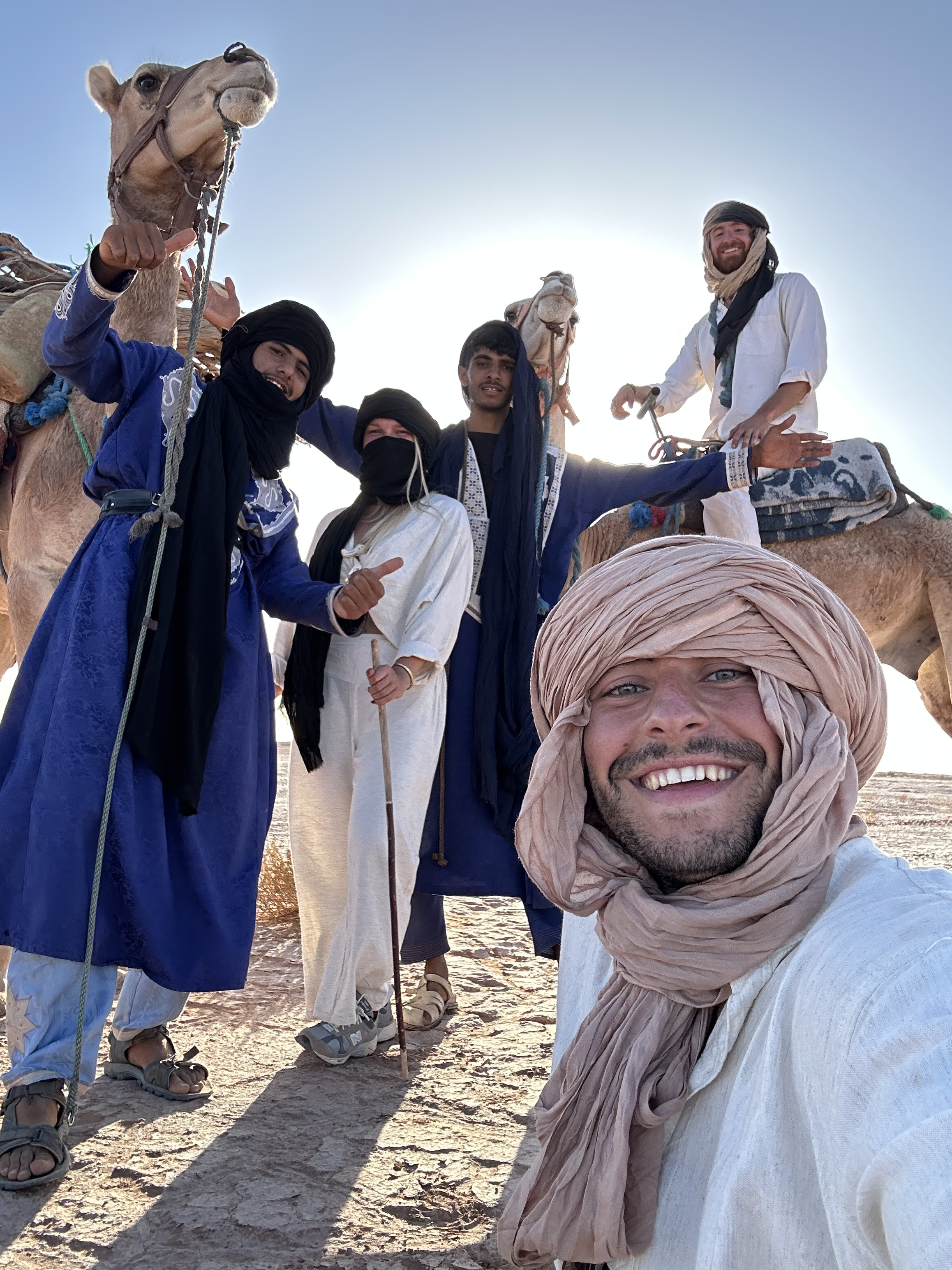 Travelers and Sahara guides smiling with camels.